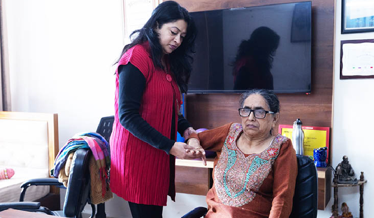 A senior patient smiling while receiving therapeutic exercises from a certified physiotherapist in a dedicated in-house therapy room.